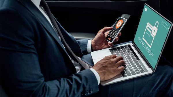 Businessman making a secure online purchase using his moblie phone and laptop