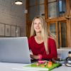 Smiling woman working alone on a laptop in a public space