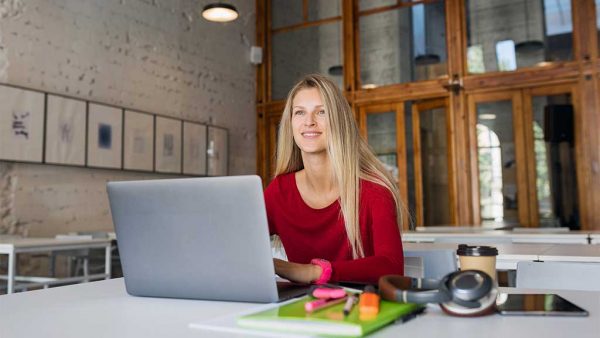 Smiling woman working alone on a laptop in a public space