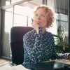 Business woman sitting in a well lit office looking into the distance thinking