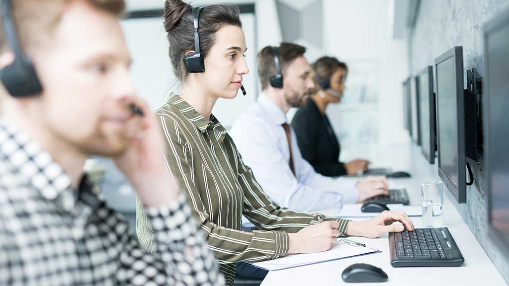 Customer service team sitting at computers answering customer phone calls