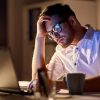 Adult sitting at desk rubbing their head trying to solve a problem