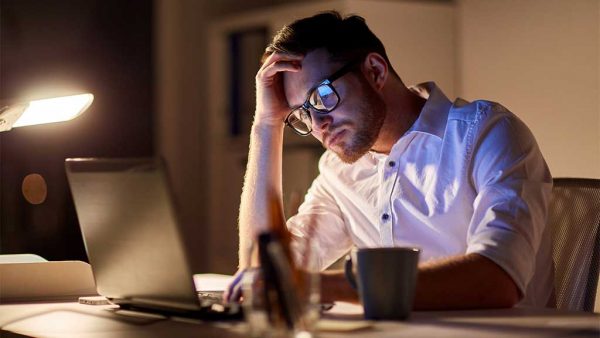 Adult sitting at desk rubbing their head trying to solve a problem