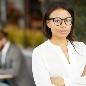 Lady with glasses standing outside smiling towards camera