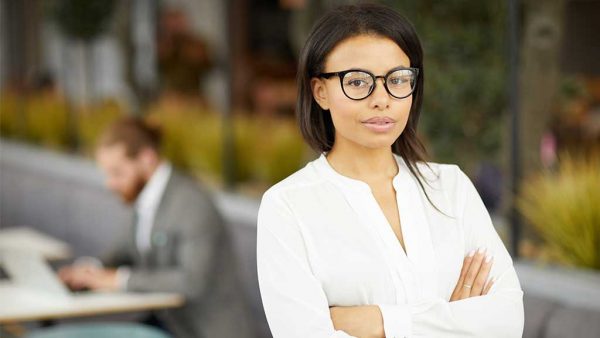 Lady with glasses standing outside smiling towards camera